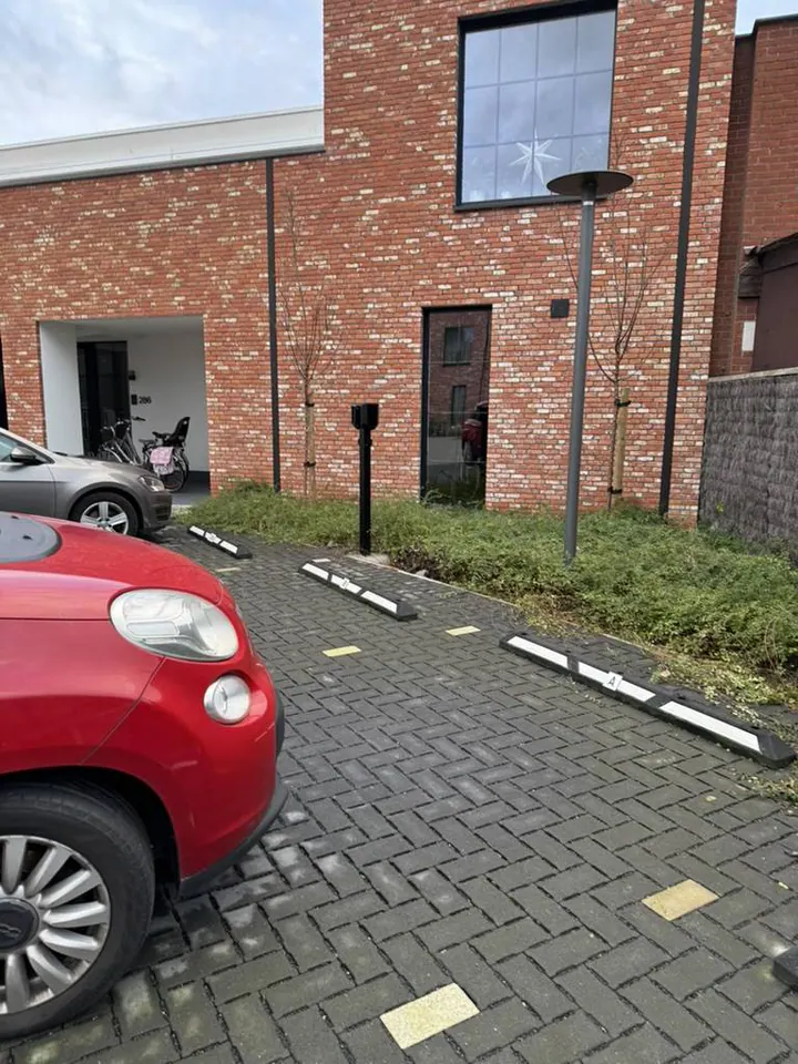 Zwarte Easee-lader op een montagepaal aan een appartementsparking, geplaatst door Laadnatie.