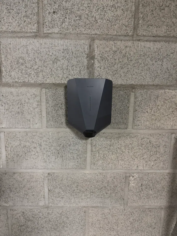 Zwarte Easee-lader aan een grijze betonstenen muur, geplaatst door Laadnatie.