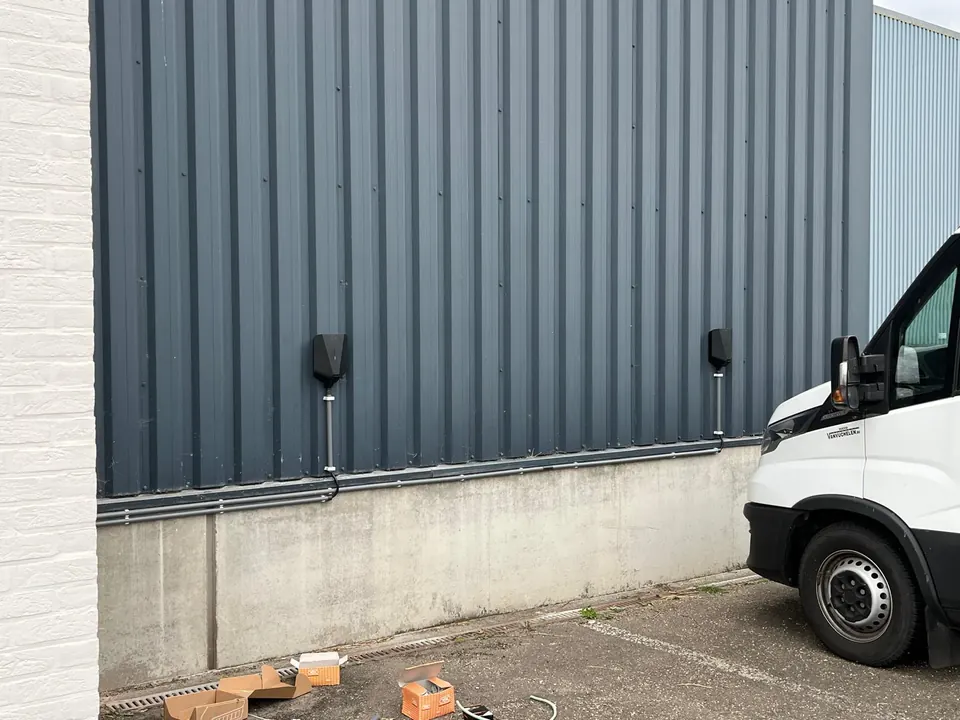 Twee zwarte Easee-laders aan een metalen bedrijfsgevel, geplaatst door Laadnatie.